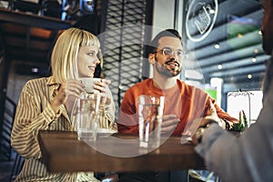 People have a great time in a cafe. Friends sitting in a coffee shop, drinking coffee, and having fun together