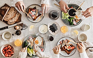 People having breakfast with coffee and snacks over white table