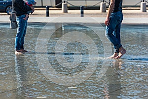 People having fun in a mirror fountain in Bordeaux, France