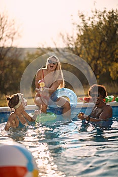 People having fun with water guns in pool at summer vacation