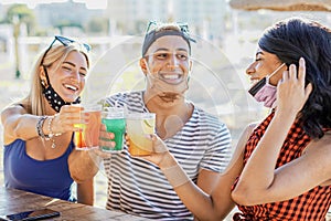 People having a party in a beach with face mask - Young people drinking cocktails in coronavirus time - Friends having fun in bar