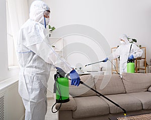 People in hazmats making disinfection in flat