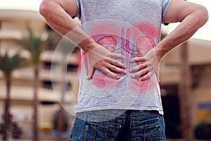 People, health care and medicine concept - unhappy man suffering from pain in back or kidneys outdoor