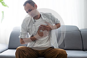 People, healthcare and health problem concept - unhappy young man having heart attack or heartache over gray background