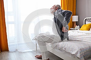people, healthcare and problem concept - sad senior man suffering from pain in back or reins at home