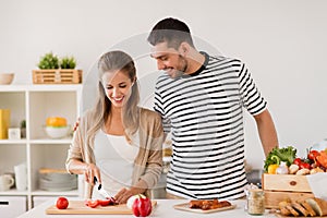 Happy couple cooking food at home kitchen