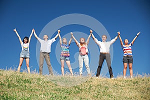 People on hill raise hands together