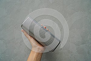 People hold Bluetooth speaker in hand for music connection with loft wall background