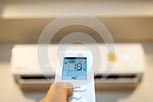 People hold a remote control with air conditioner,hand turn on the air conditioner,adjust the temperature to 18 degrees celsius on photo