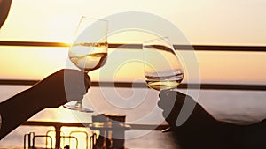 People holding glass of wine, making a toast over sunset. Party outdoors. Enjoying time together.