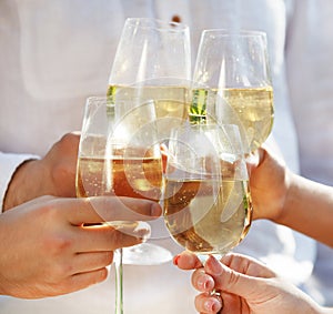 People holding glasses of white wine making a toast