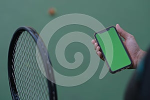 People holding green screen smart phone while holding tennis racket