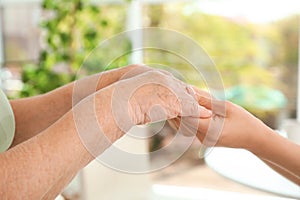 People holding hands together on blurred background. Help and elderly care concept