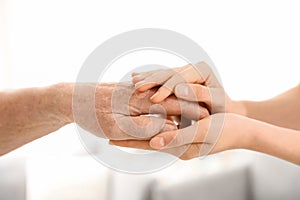 People holding hands together on blurred background. Help and elderly care concept