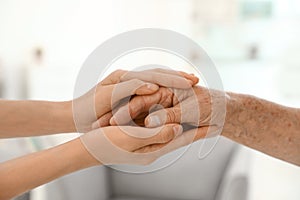 People holding hands together on blurred background. Help and elderly care concept