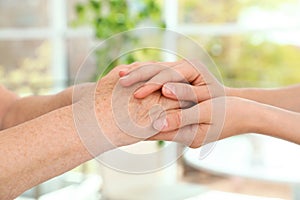 People holding hands together on blurred background. Help and elderly care concept