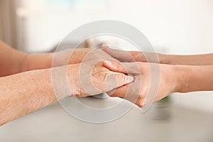 People holding hands together on blurred background. Help and elderly care concept