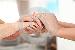 People holding hands together on blurred background. Help and elderly care concept