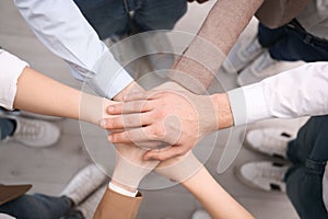People holding hands together in office, top view