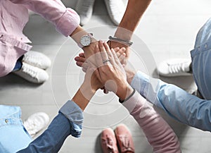 People holding hands together over light, top view. Unity concept