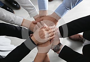 People holding hands together over light, top view. Unity concept