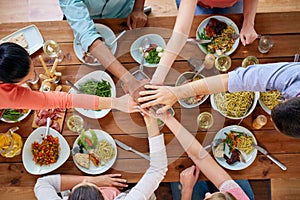 People holding hands together over table with food