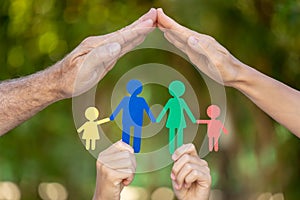 People holding paper family in hands against spring green background