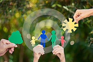 People holding paper family in hands against spring green background