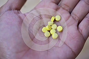 People holding Yellow pills placed on hand