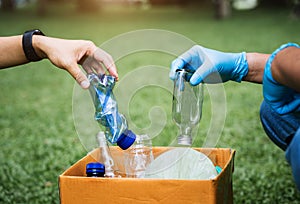 People holds plastic and glass waste bottles into recycling bags for cleaning at the park