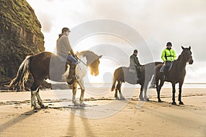 People with horses on the beach on a cloudy day