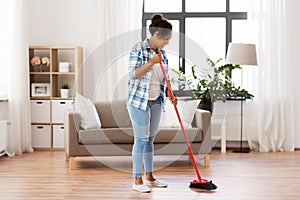 Woman with sweeping broom brush cleaning floor