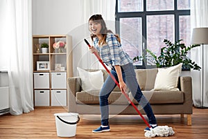 Happy asian woman with mop cleaning floor at home