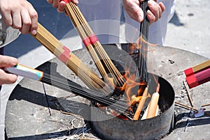 People ignite bundles of incense sticks