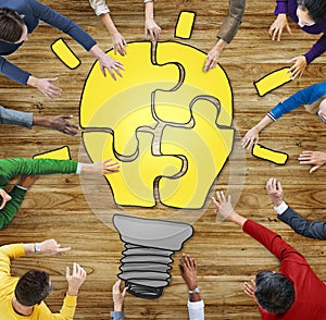 People with Jigsaw Puzzle Forming Light Bulb