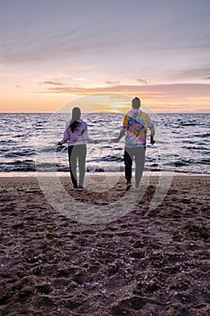 People with jumprope exersise on the beach, couple men and woman exersise together outsied on the beach in the photo