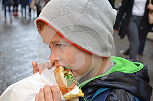 People, junk food, eating and lifestyle - close up of young man, boy with sandwich eating and drinking on city street