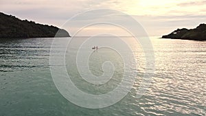 People kayaking in calm sea when sunset. small boat paddling in the bay near tropical island.