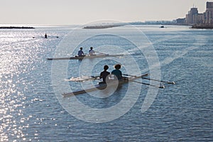 People on kayaks in pairs in the sea at sunrise in Italy