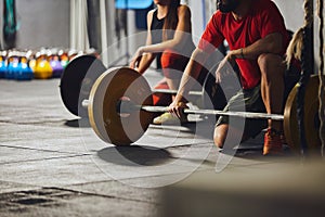 People kneeling in front of barbells