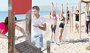 People leading healthy lifestyle, doing exercises on ocean beach at daytime