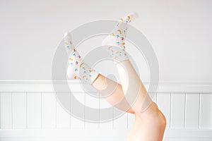 People Legs Up  on White Bedroom Studio. Closeup of the Bare Leg of a Beautiful Young Woman Wearing Bright Cute Pastel