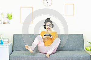 People and leisure concept - happy smiling asian young woman with gamepad playing video games on console having fun, resting on