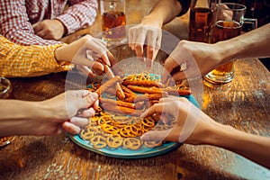 People, leisure, friendship and communication concept - happy friends drinking beer, talking and clinking glasses at bar