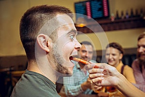 People, leisure, friendship and communication concept - happy friends drinking beer, talking and clinking glasses at bar