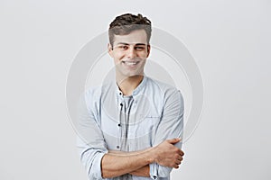 People and lifestyle concept. Attractive young caucasian male in good mood, in blue long sleeved shirt smiling