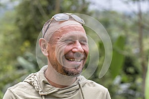 People and lifestyle concept. Happy middle-aged unshaven man with cheerful smile outdoor against green nature background, portrait