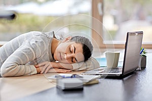 Tired woman sleeping on table with laptop at home