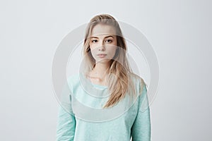 People and lifestyle. Studio shot of attractive young Caucasian dark-eyed female with long dyed blonde hair posing