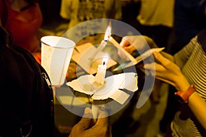 People lighting candle vigil in darkness seeking hope, worship,